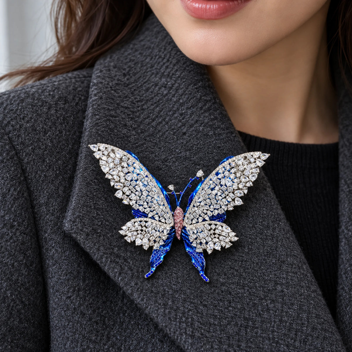 Tilda butterfly brooch pinned inside a broad charcoal wool coat lapel.