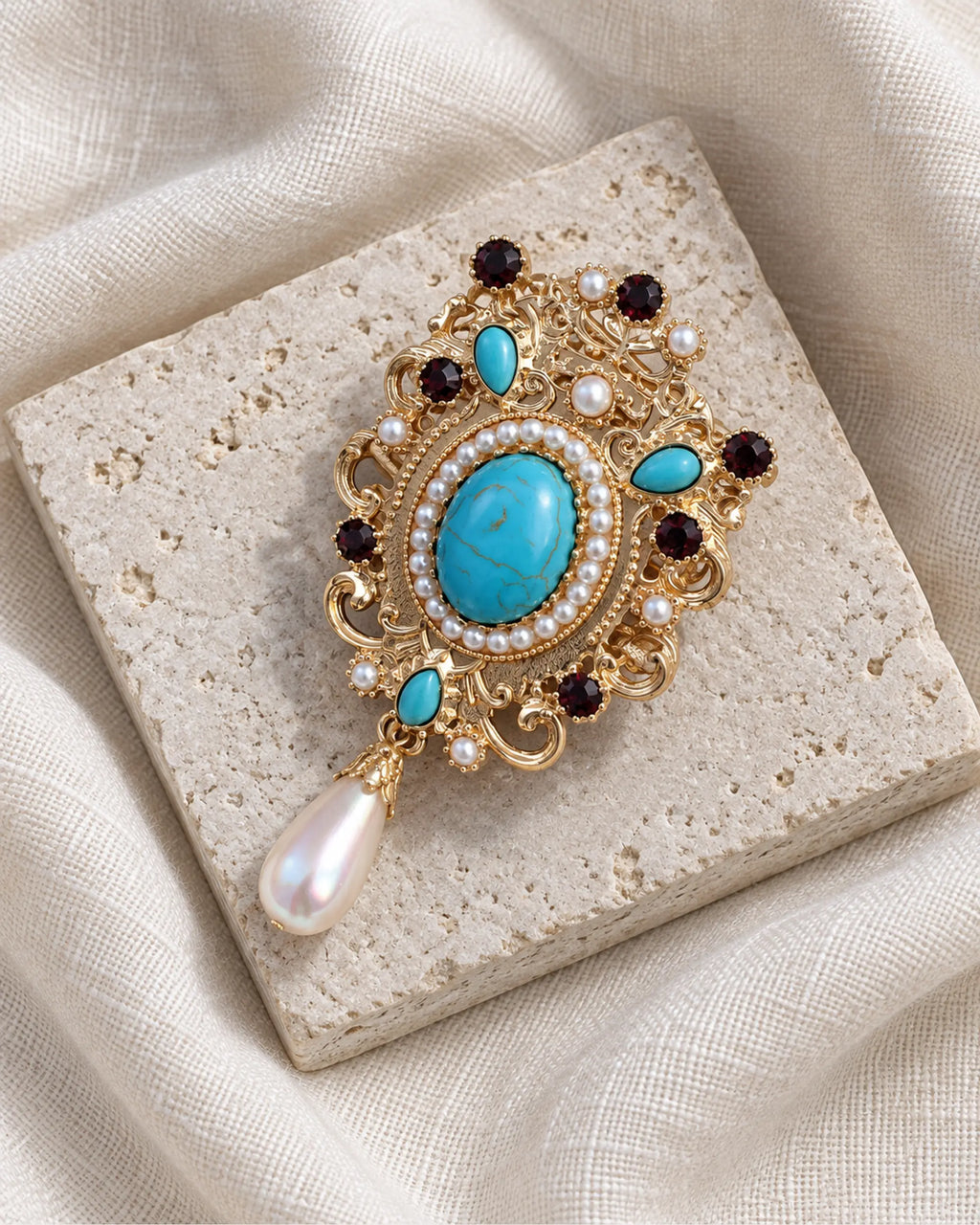 Tove Turquoise-Blue Scroll Drop Brooch — front view on a stone tile and ivory linen