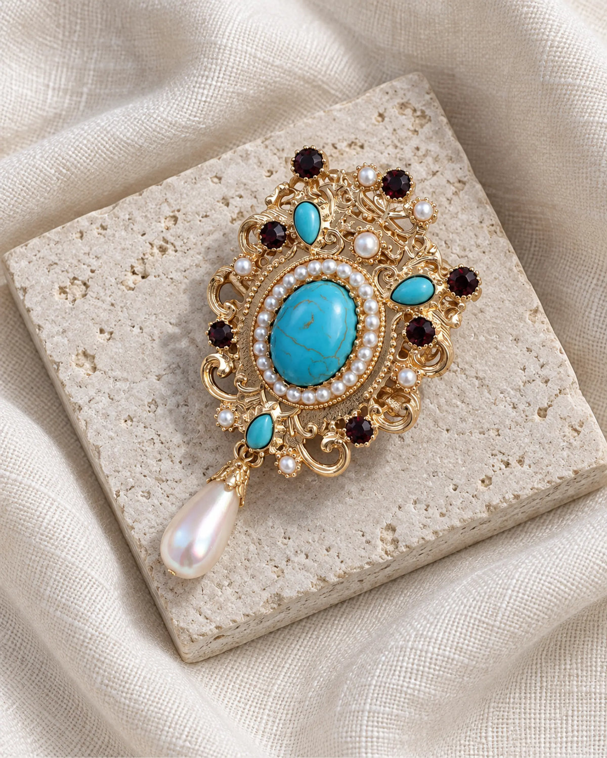 Tove Turquoise-Blue Scroll Drop Brooch — front view on a stone tile and ivory linen