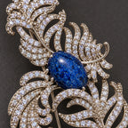 Small clear zircon follow the open ribs around the mottled deep-blue oval accent.
