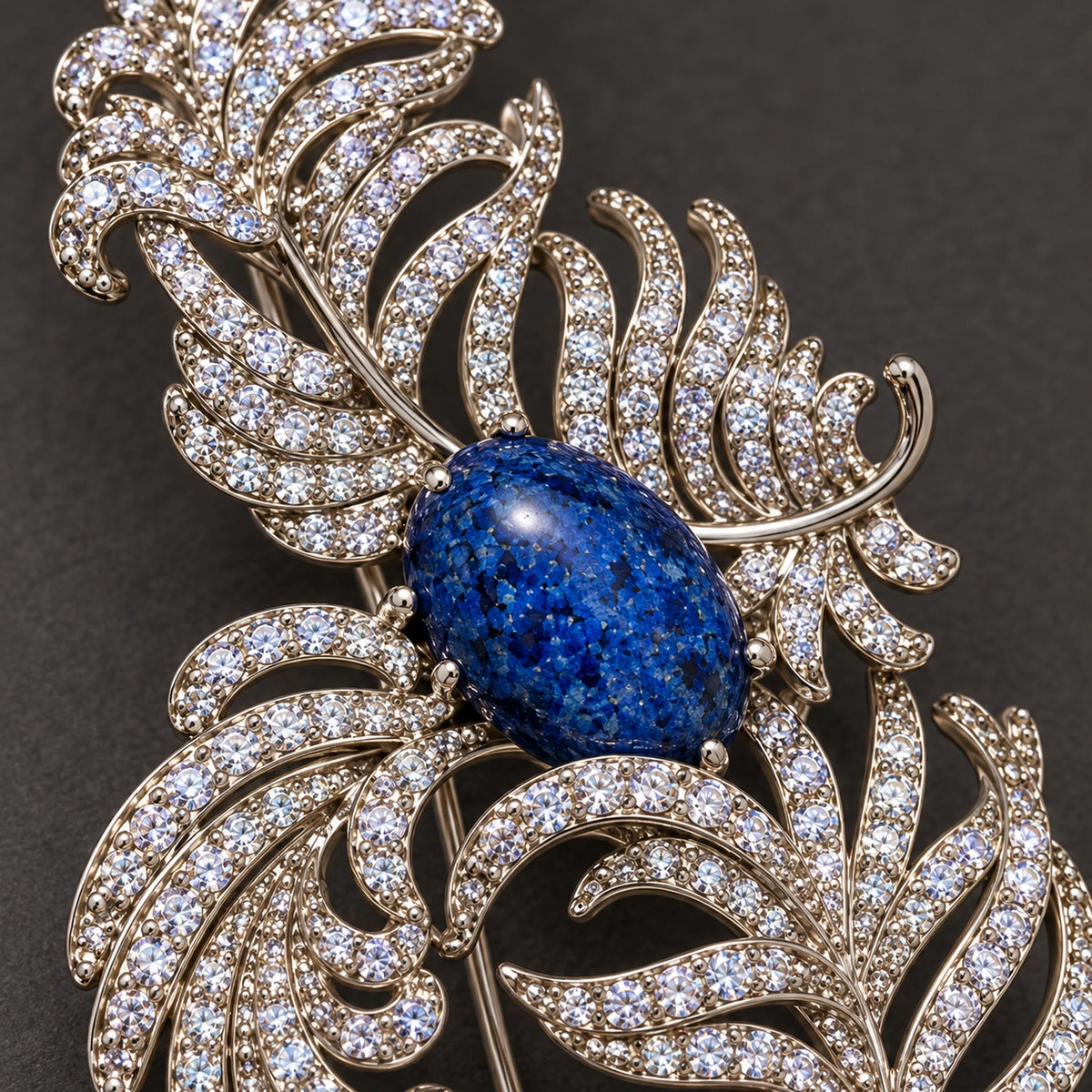 Small clear zircon follow the open ribs around the mottled deep-blue oval accent.