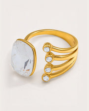 Atrium Adjustable Gold Crystal Ring on a soft warm grey background