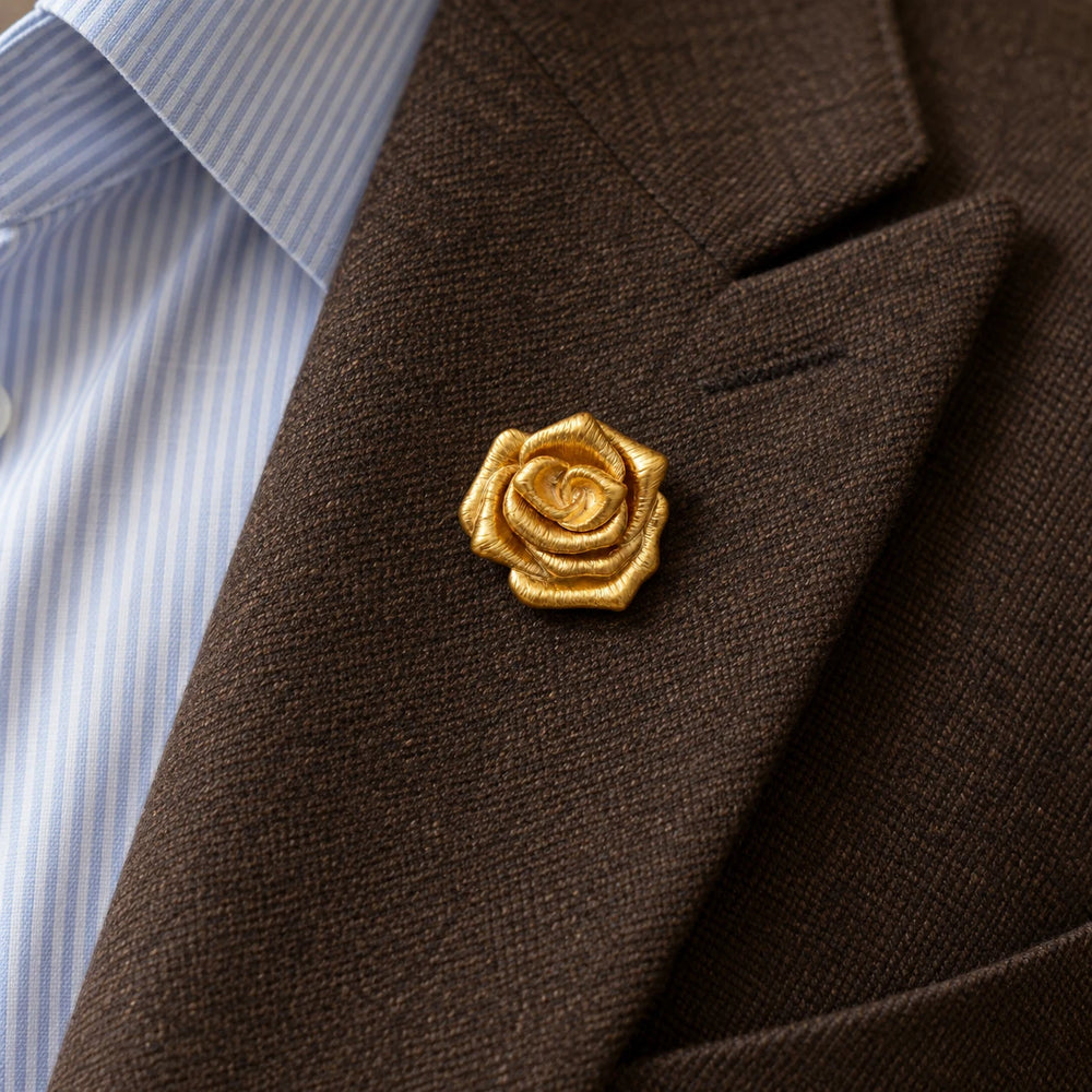Taimi gold flower brooch on a brown wool lapel with a blue striped shirt