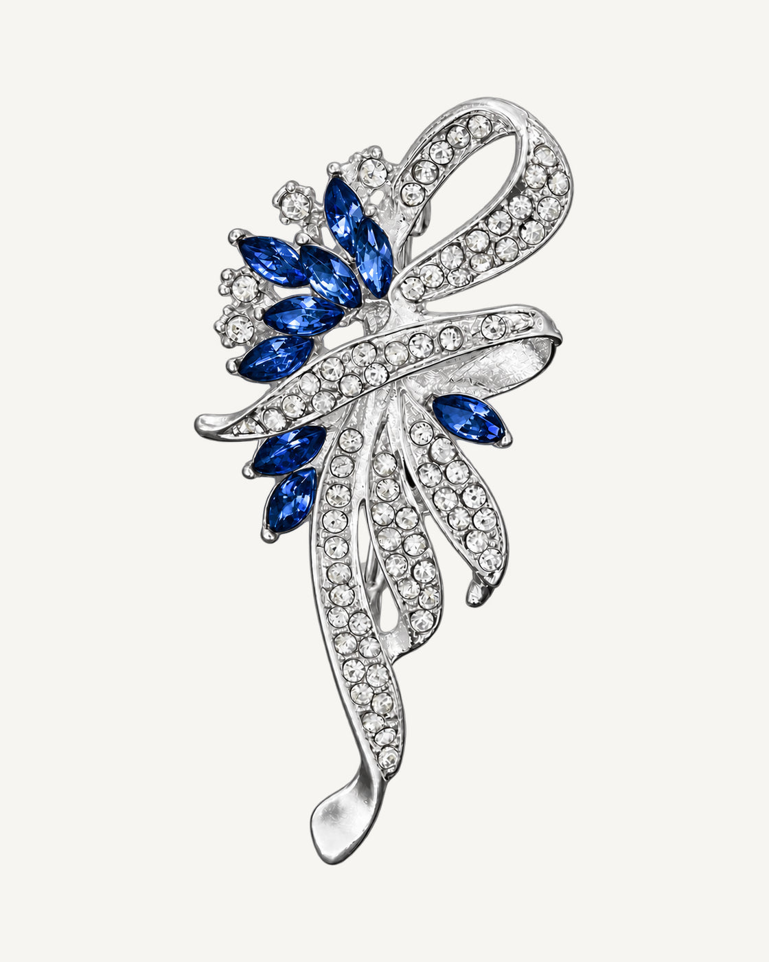 Elowen Crystal Spray Brooch in silver and sapphire blue on an exact #EDE3D4 background