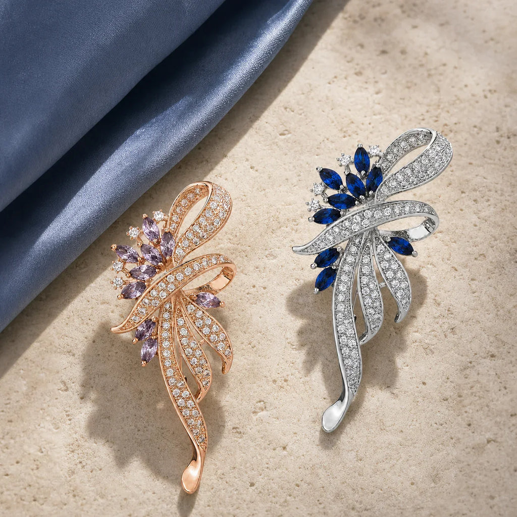 Both Elowen Crystal Spray Brooch colorways arranged in a limestone and silk still life