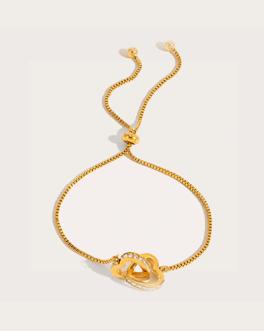 Lovi Adjustable Gold Heart Knot Bracelet on a soft warm grey background