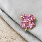 Lykke Pink Clover Brooch resting on dove-gray silk and travertine