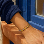 Nila Lapis Charm Bracelet worn beside a cobalt blue window