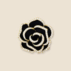 Noir Camellia Brooch in gold, black and clear zircon on an exact #EDE3D4 background