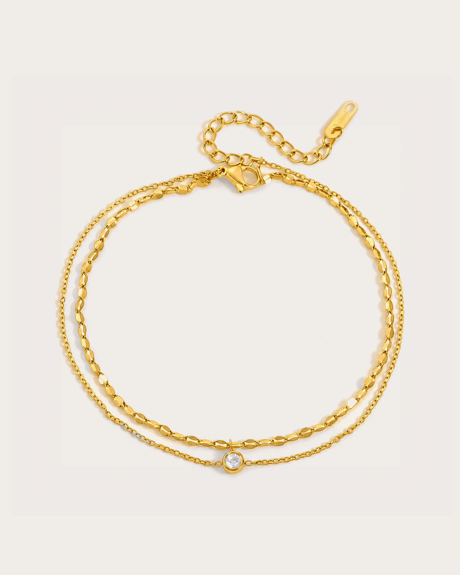 Selene Gold Double-Chain Crystal Anklet on a soft warm grey background