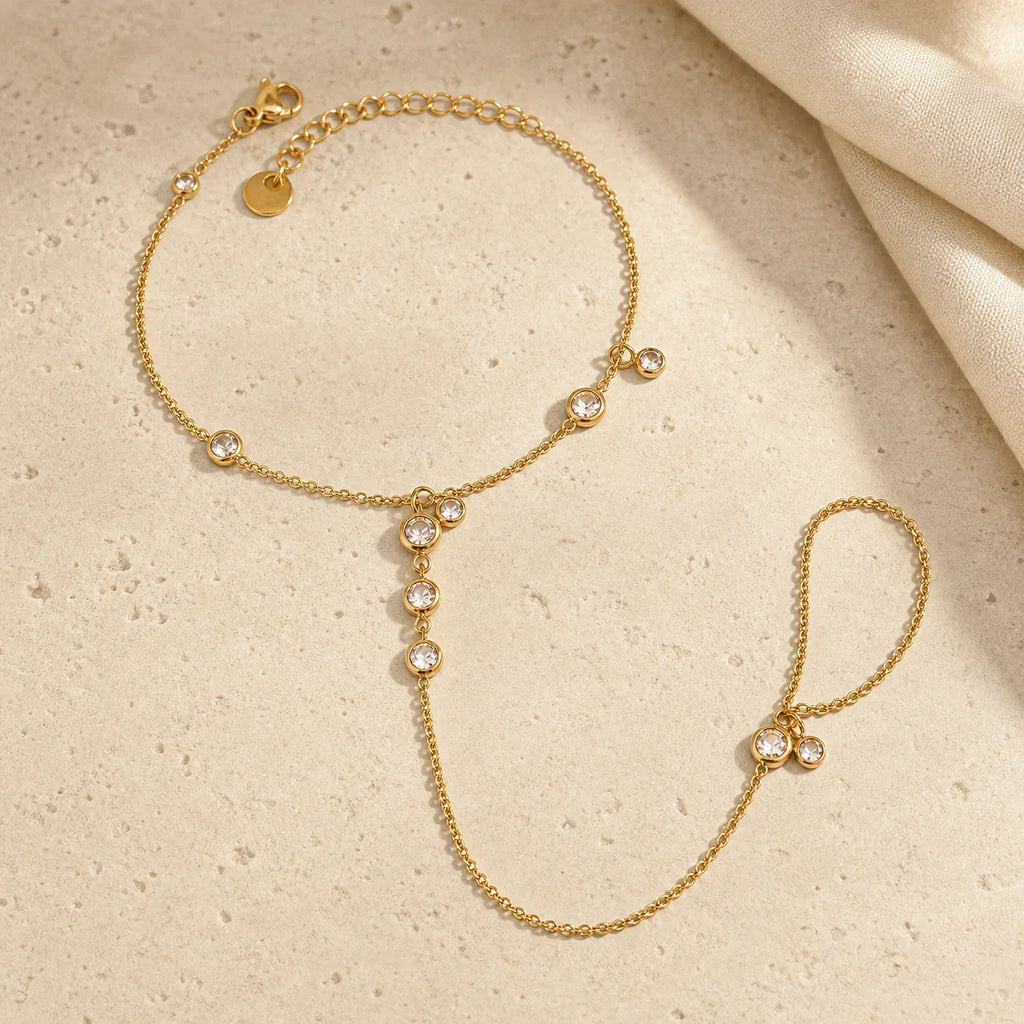 Gold-tone Siro Crystal Hand Chain arranged on travertine with its clasp, extender, connector chain and finger loop visible