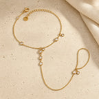 Gold-tone Siro Crystal Hand Chain arranged on travertine with its clasp, extender, connector chain and finger loop visible