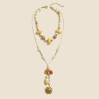 Solara Layered Talisman Necklace displayed in full on an exact #EDE3D4 background
