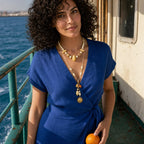 Solara Layered Talisman Necklace worn with a cobalt linen dress on an island ferry