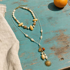 Solara Layered Talisman Necklace arranged on a weathered turquoise table in sunlight