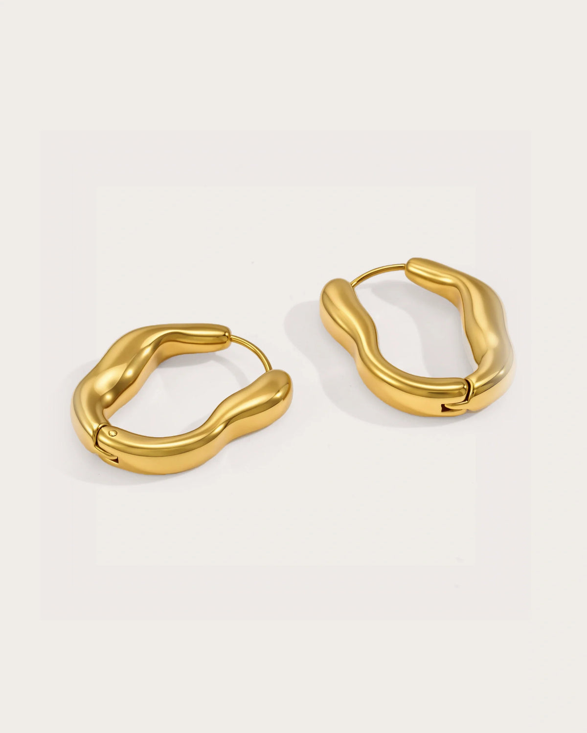 Vela Current Hoop Earrings on a soft warm grey background