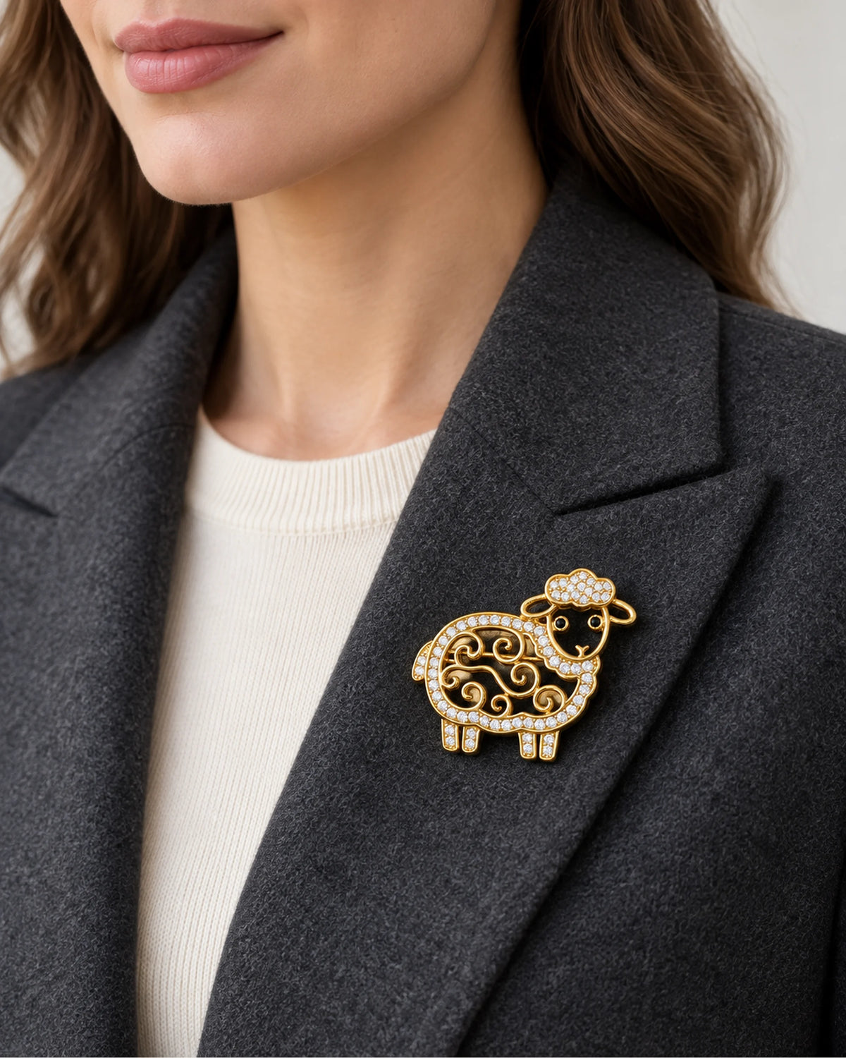 Gold openwork sheep brooch worn on a charcoal blazer lapel