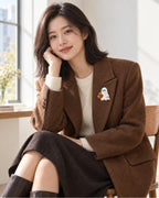 Usva's white silhouette stays clear against a brown blazer and cream knit.