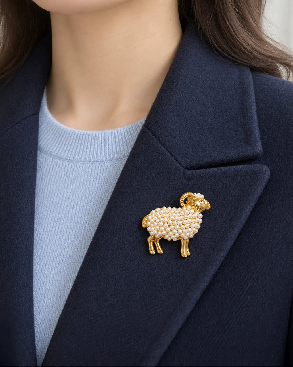 White imitation pearl ram brooch worn on a navy blazer lapel