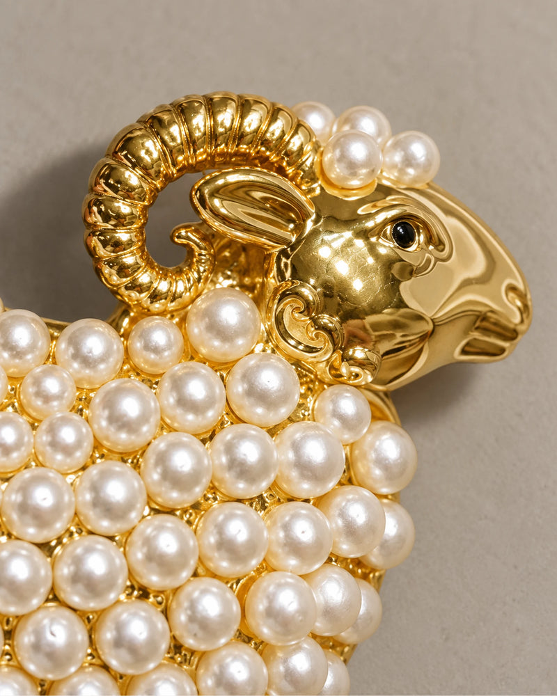 Macro of the curled gold-tone horn and white imitation pearls