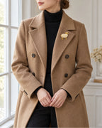 Imitation pearl ram brooch worn on a camel coat, wider view