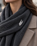 Silver Vinga twin wing brooch secured to a charcoal scarf worn with a taupe coat.