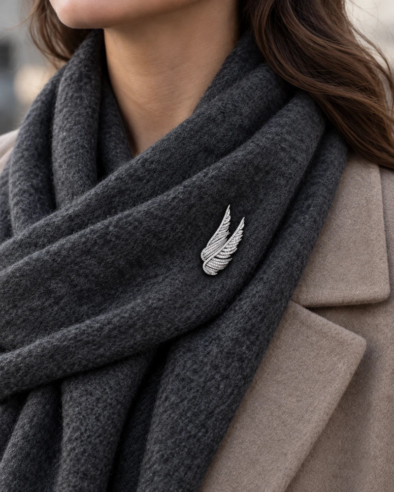 Silver Vinga twin wing brooch secured to a charcoal scarf worn with a taupe coat.