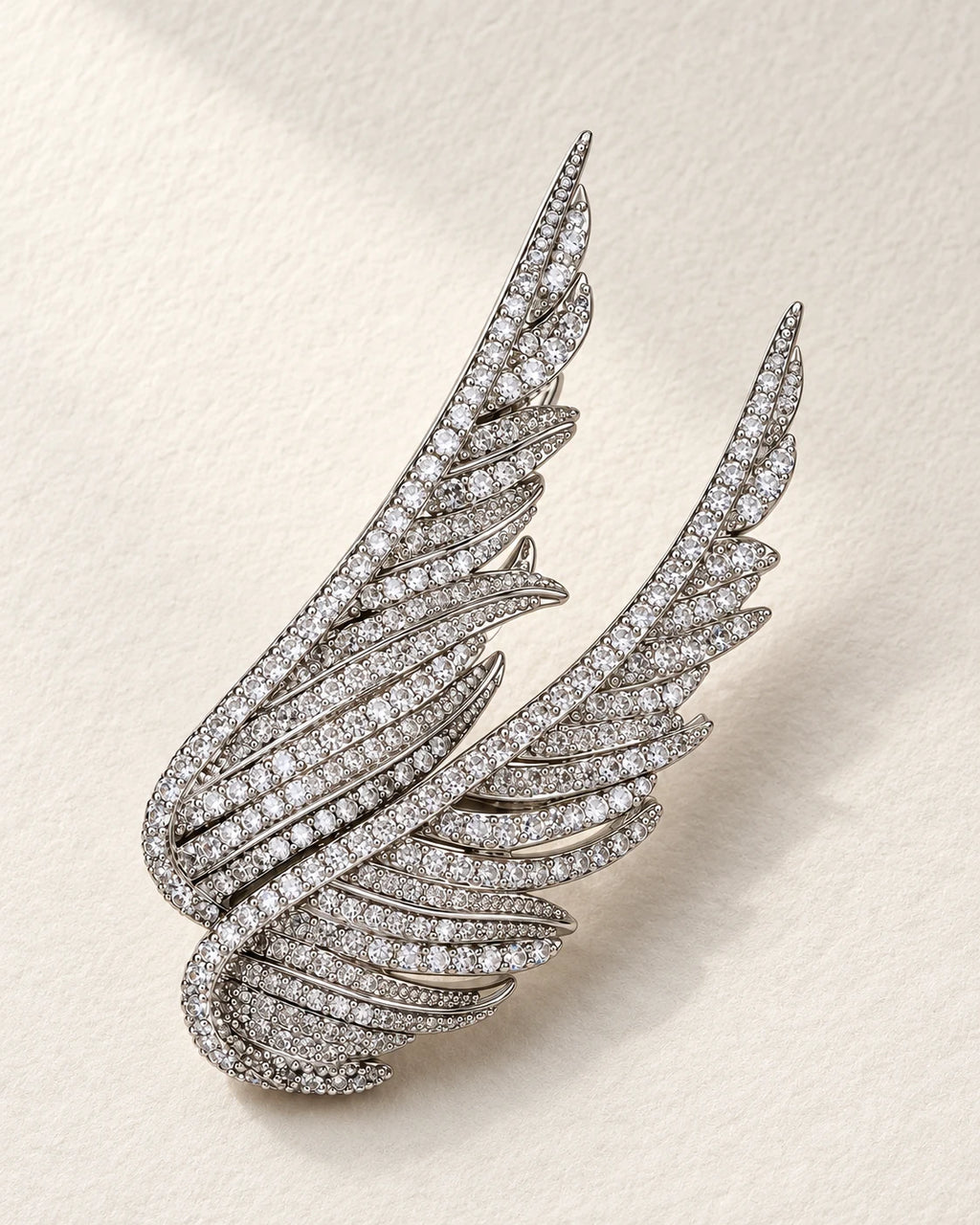 Silver Vinga twin wing brooch resting on ivory textured paper.
