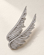 Silver Vinga twin wing brooch resting on ivory textured paper.