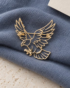 Vinge openwork eagle brooch resting on slate blue fabric and limestone